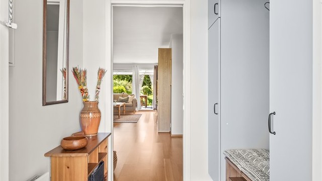 Ytterdøren er utstyrt med kodelås for nøkkelfri adkomst. Inne møter du en romslig entré med garderobeskap langs den ene veggen, med god plass til yttertøy og sko.