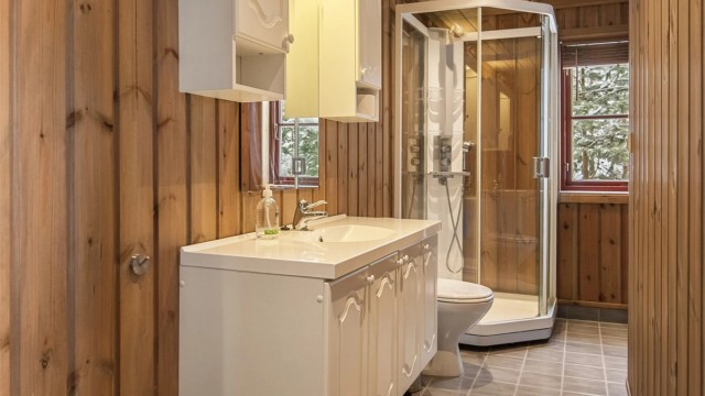 Badet i første etasje har flislagt gulv med gulvvarme, dusjkabinett og opplegg for vaskemaskin.