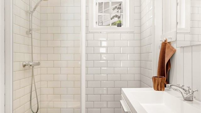 Badet i gjesteavdelingen har flislagt gulv med gulvvarme og dusjhjørne med glassvegger.