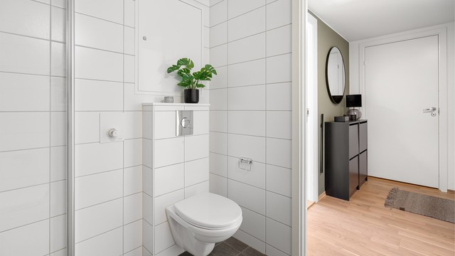 Badet er utstyrt med vegghengt servantinnredning, ovenpåliggende servant med armatur, vegghengt toalett , speil med overlys og stikkontakt over servant.