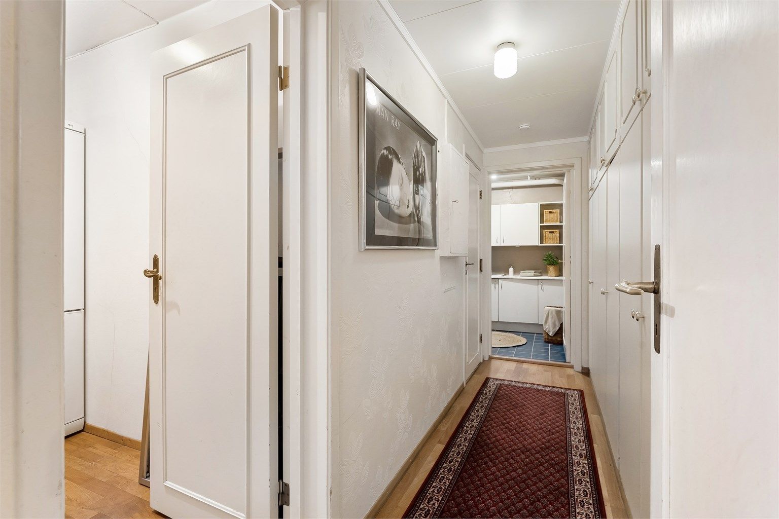 Gangen i underetasjen har tapetserte vegger og leder videre til blant annet vaskerommet.