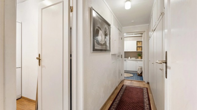 Gangen i underetasjen har tapetserte vegger og leder videre til blant annet vaskerommet.