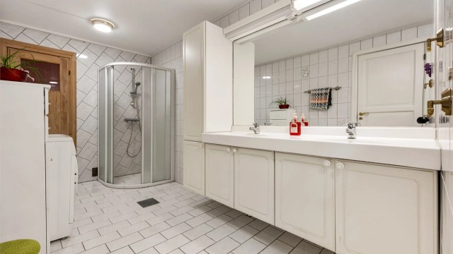 Stort, flislagt bad med elektrisk gulvvarme, doble servanter og opplegg for vaskemaskin.