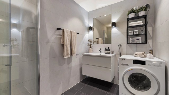Badet er innredet med vegghengt servantinnredning med ovenpåliggende vask og speil med lys over vasken.