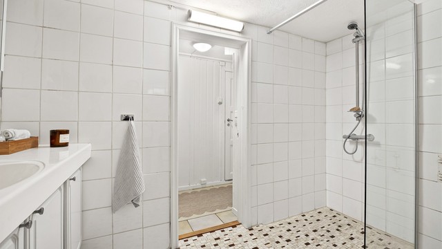Dusj i hjørne med veggmontert dusjarmatur og dusjvegg av glass (dusjvegg fra 2023).