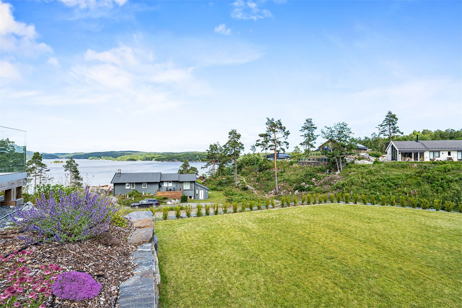 Pent opparbeidet tomt med hekk, plen. Stor terrasse.