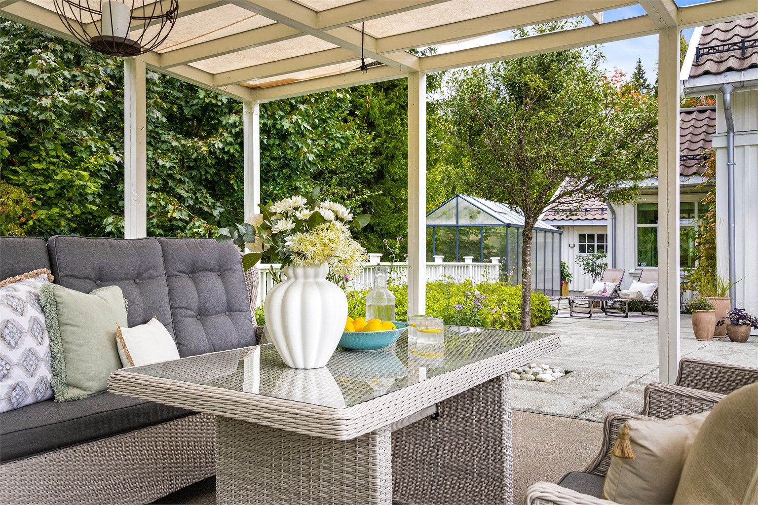 Fra uteplassen har man utsyn mot bl.a. hagen og drivhuset.