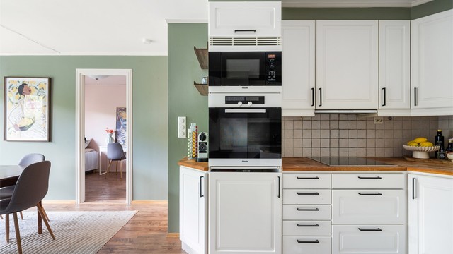 Kjøkkeninnredningen er i hvite, profilerte skapfronter med benkeplate i tre med nedfelt kjøkkenvask. Det er integrerte hvitevarer som stekeovn med platetopp og frittstående oppvaskmaskin, vaskemaskin og kjøleskap med fryser.