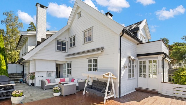 Stor og solrik terrasse med utepeis og trapp til hagen