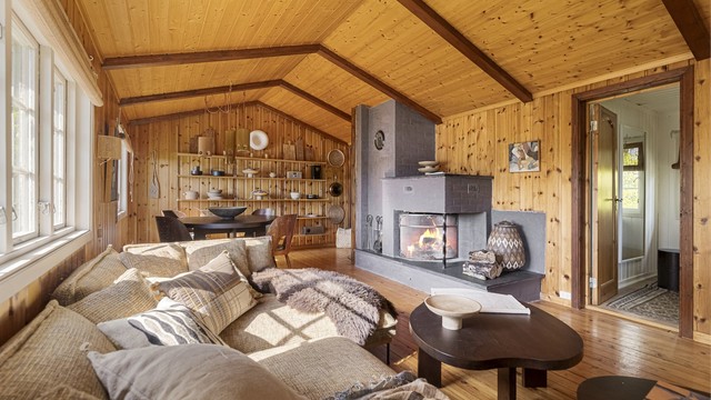 Stuen har rikelig med plass til både sofagruppe og spisebord. Den åpne peisen og vedovnen er perfekt for både varme og hygge på kalde dager.