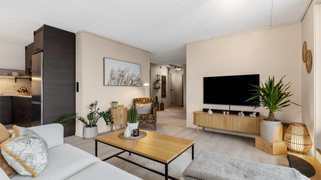 Den åpne løsningen mellom stue og kjøkken skaper en sosial og luftig atmosfære.