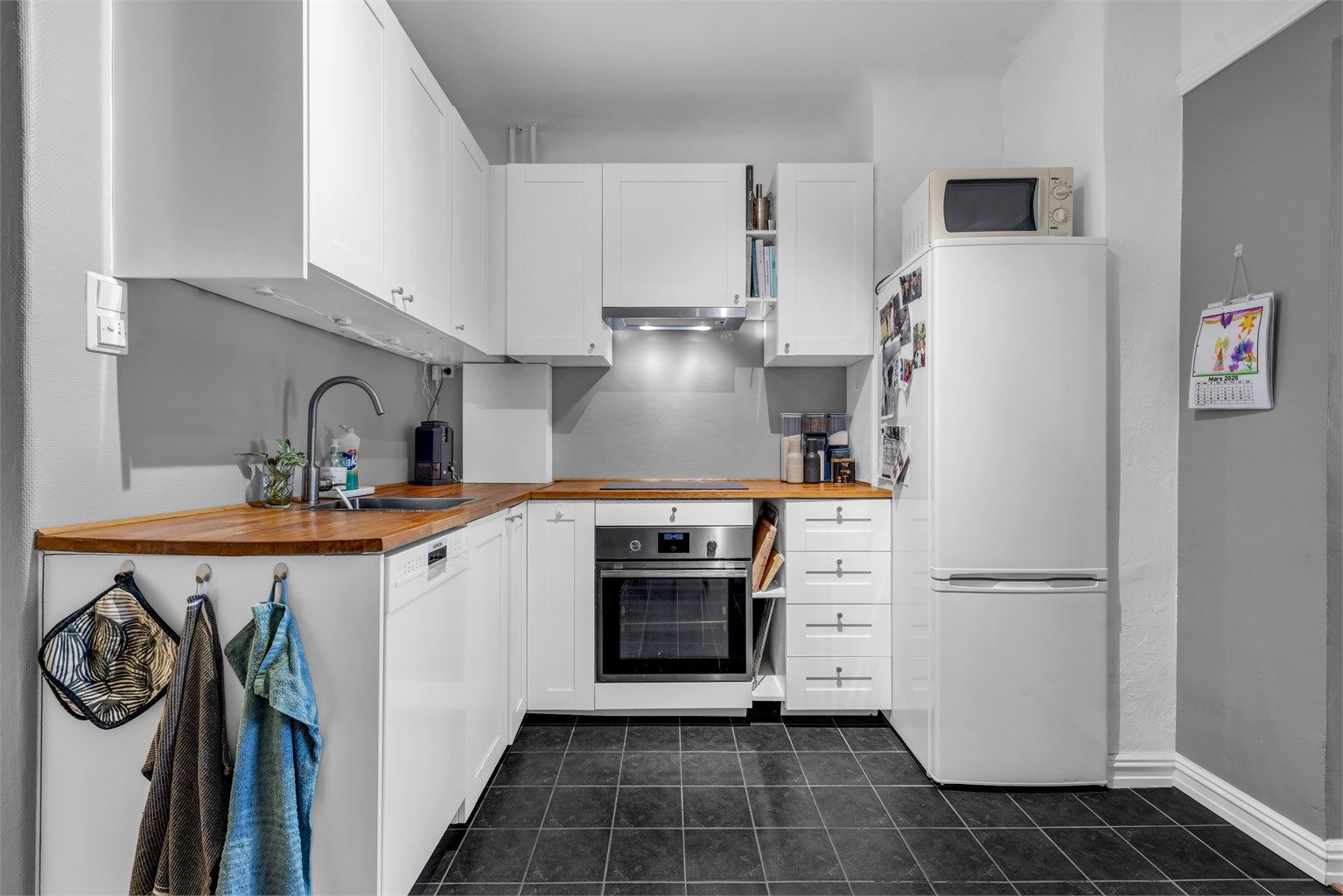 Kjøkkenet er innredet med profilerte skapfronter og benkeplate i treverk/laminat med trestruktur og nedfelt oppvaskkum i benkeplaten.