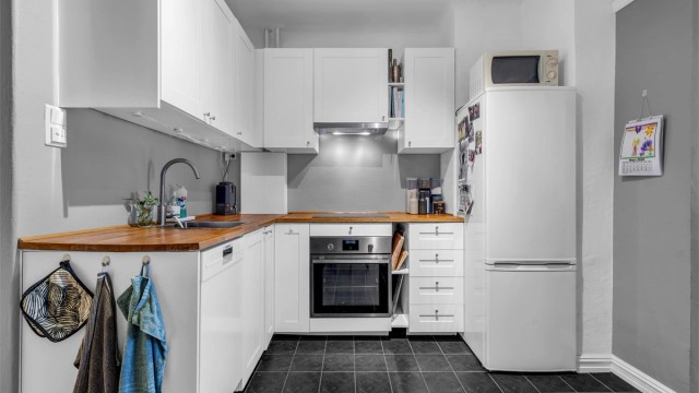 Kjøkkenet er innredet med profilerte skapfronter og benkeplate i treverk/laminat med trestruktur og nedfelt oppvaskkum i benkeplaten.