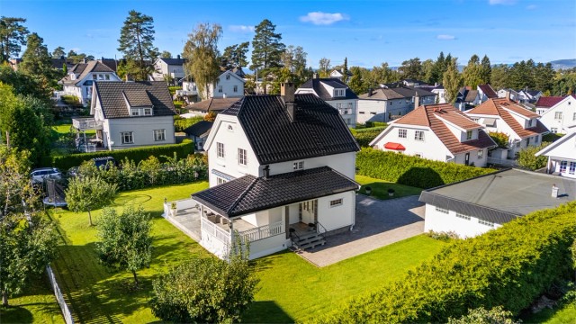 Hele tomten er inngjerdet med hhv. stakittgjerde og hekk, samt port i innkjørselen