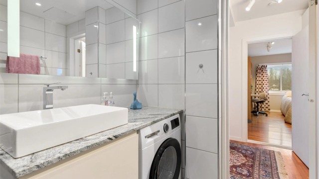 Innredningen består av et vegghengt servantskap, speil med belysning og opplegg for vaskemaskin.