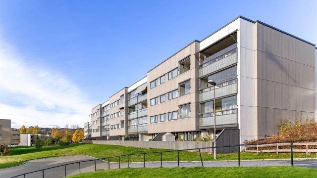 Boligblokken er oppført i 1977 med fasadeplater, grøntanlegg og gangveier rundt bygget.