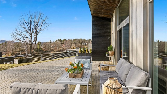 Stor skyvedør i glass fra stue og kjøkken fører ut på terrassen.