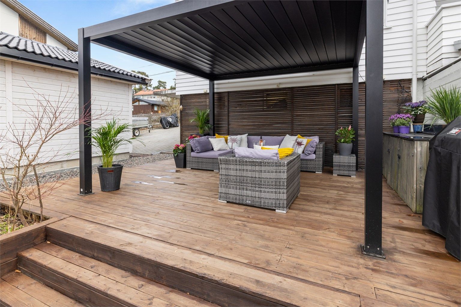 En nyere pergola skaper en lun og definert sone i hagen, perfekt for sosiale sammenkomster.