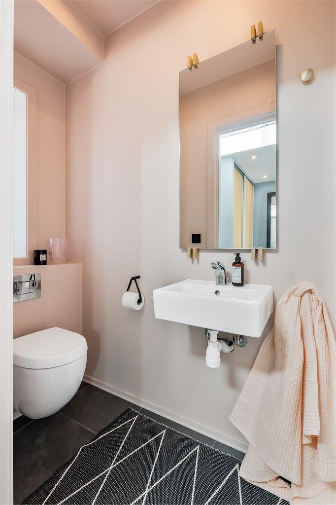 Toalettrom med flislagt gulv og vegger i malte flater. Nedsenket himling med downlights. Vegghengt servant med ett-greps armatur. Speil på vegg over servant. Vegghengt toalett. Mekanisk avtrekksventil i himling.