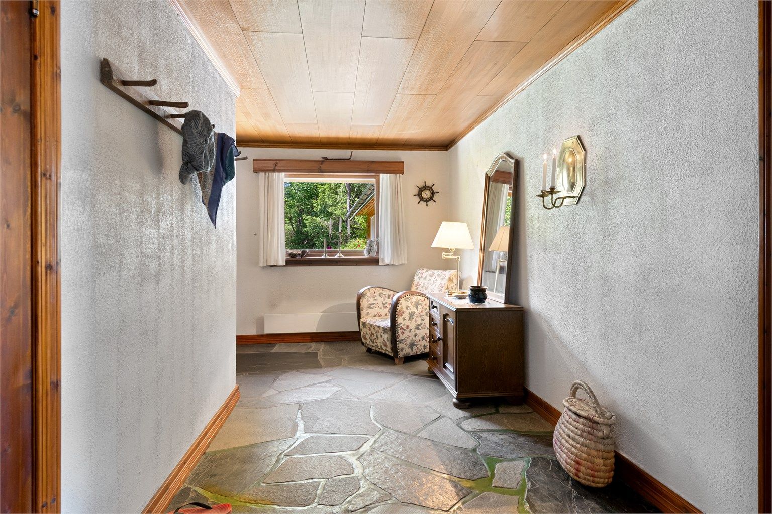 Romslig gang/entre med skifer på gulv, malte murvegger og panelplater i himling