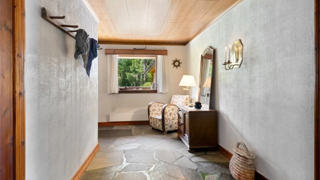Romslig gang/entre med skifer på gulv, malte murvegger og panelplater i himling