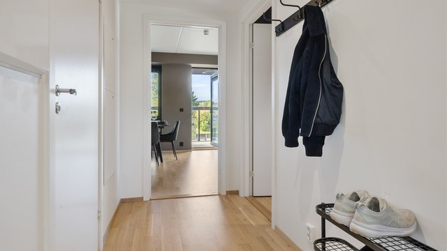 Gangen leder videre inn til leilighetens åpne stue og kjøkken.