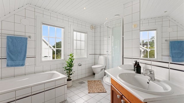 Badet er utstyrt med både badekar og dusjkabinett, samt to servanter.