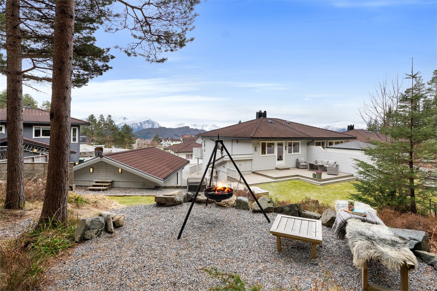 Tomten er opparbeidet med grus, plenarealer og diverse beplantninger - koselig uteplass i skogen like utenfor tomtegrense med bålplass (friareal)