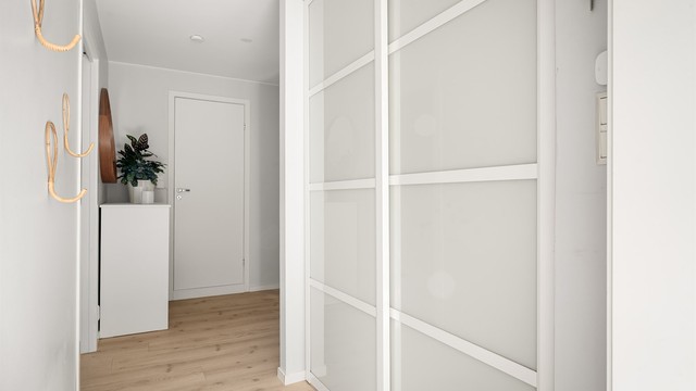 Entré med plassbygget garderobe med skyvedører.