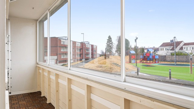 Balkongen er i en høy 1. etg., og utenfor ligger en hyggelig nyoppusset lekeplass