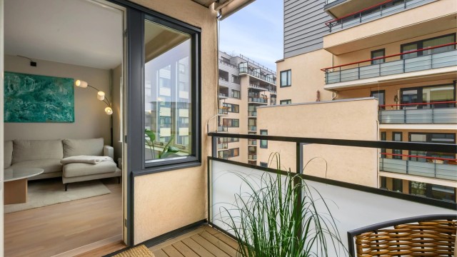 Gulvet er belagt med terrassebord, og rekkverket er i metall og glass.