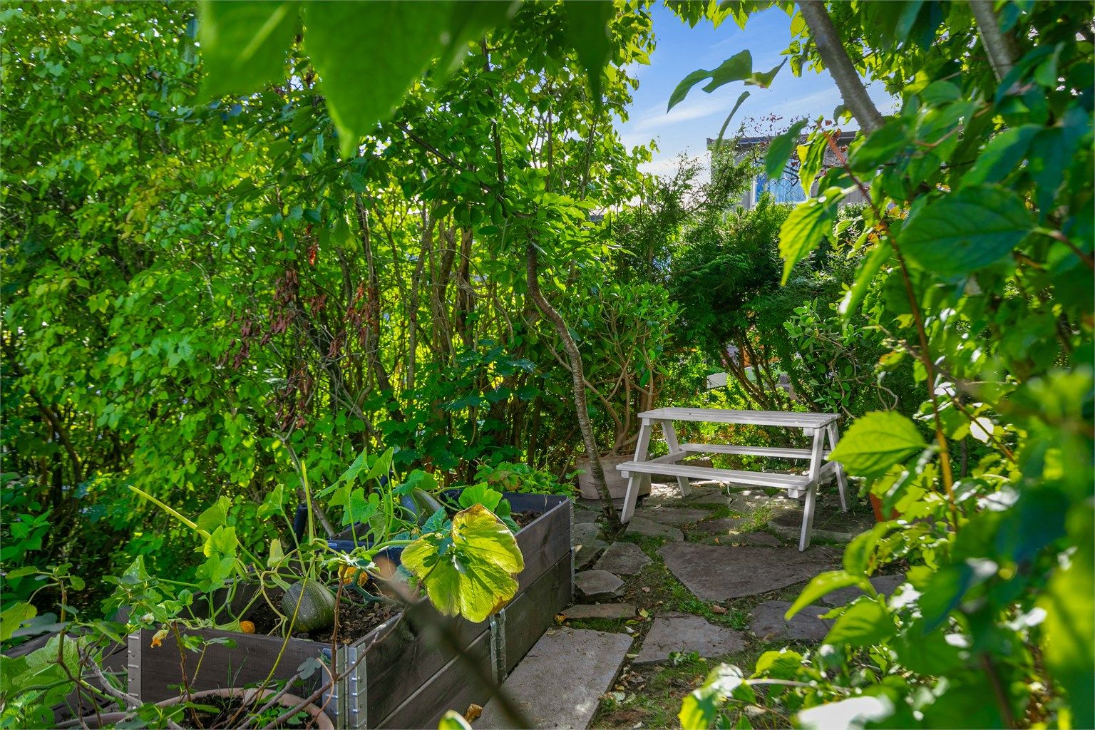Frittliggende sitteplass og pallekarmer for dyrking i hageområdet.