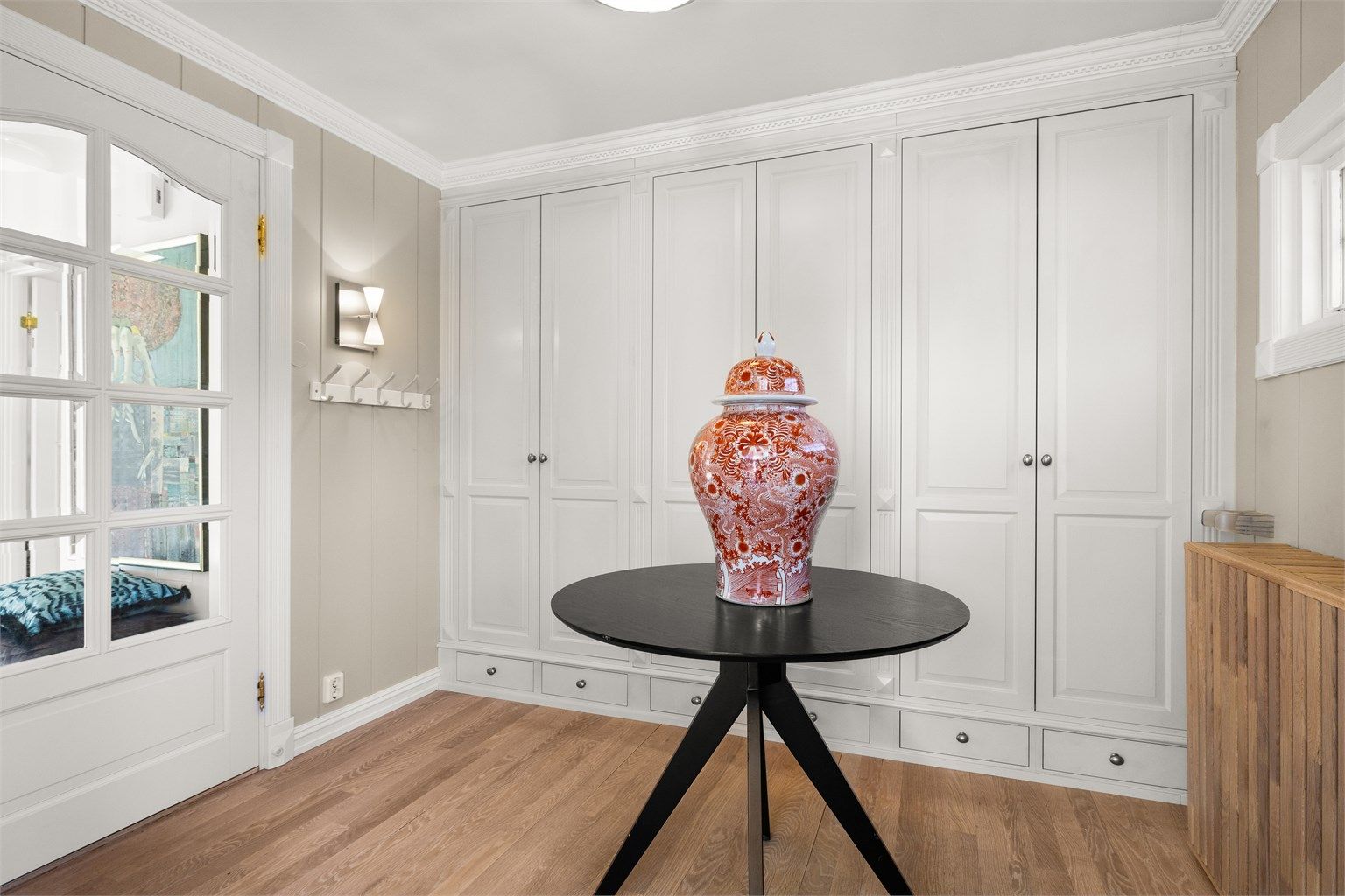 Romslig entré med rikelig med plassbygde garderobeskap. Doble glassdører mellom entréen og hallen