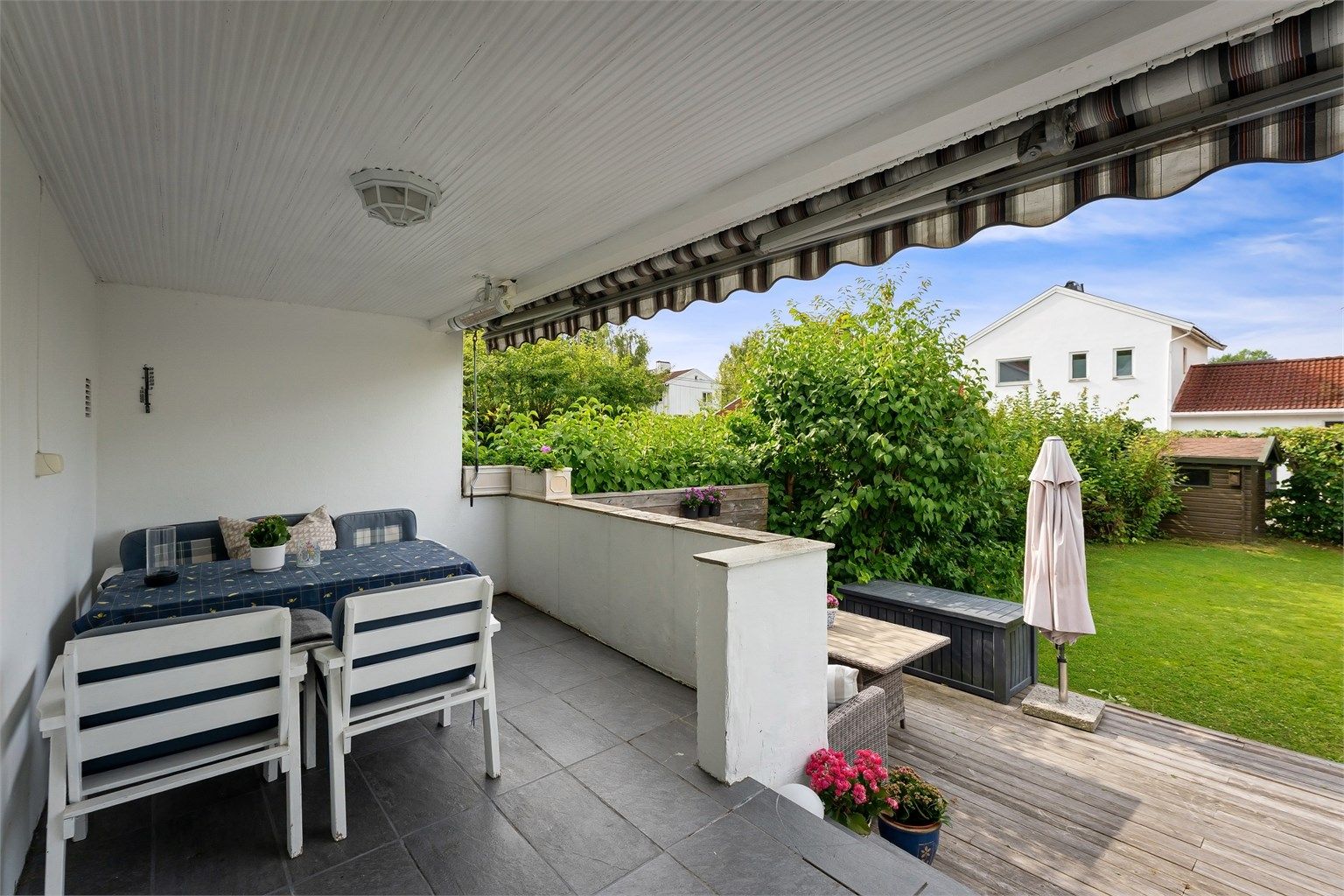 Overbygget veranda på 11 m² med markise, varmelampe og plass til spisebord.