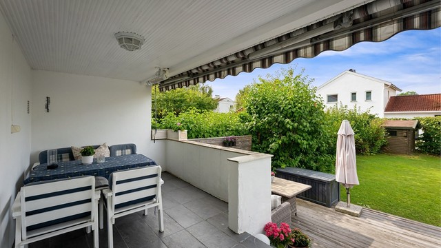 Overbygget veranda på 11 m² med markise, varmelampe og plass til spisebord.