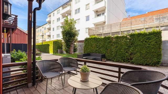 Hyggelig bakgård med stor, grønn hekk som gjør bakgården til en grønn lomme.
