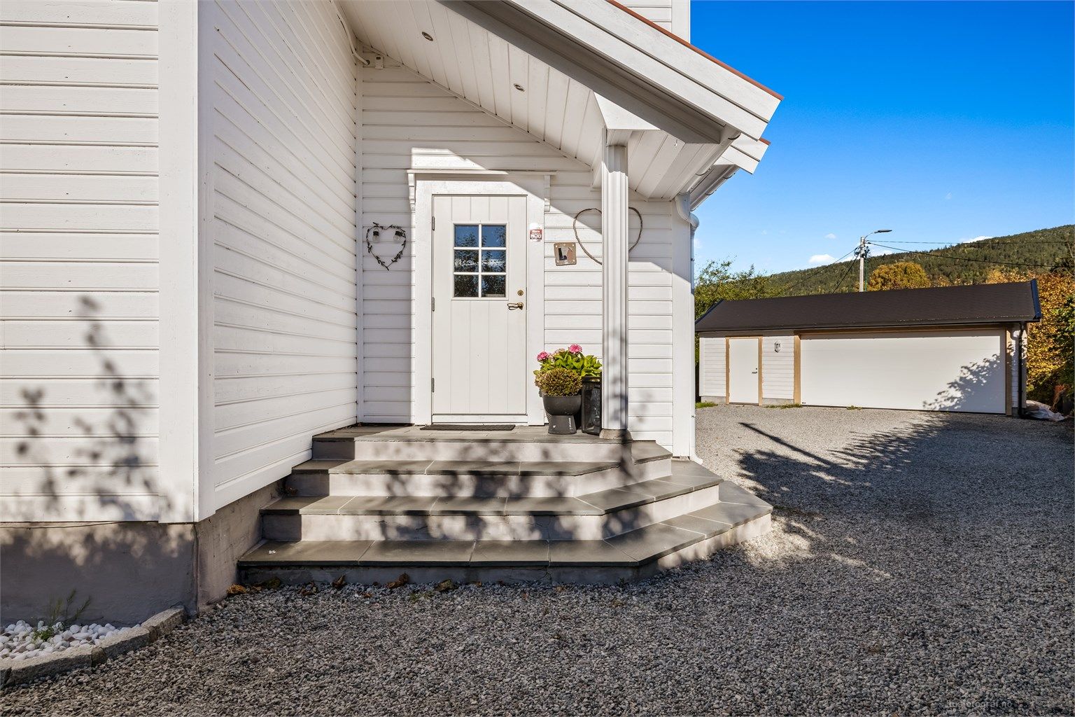 Fra gårdsplassen er det skiferbelagt trappeadkomst til boligens overbygde inngangsparti i 1. etasje.