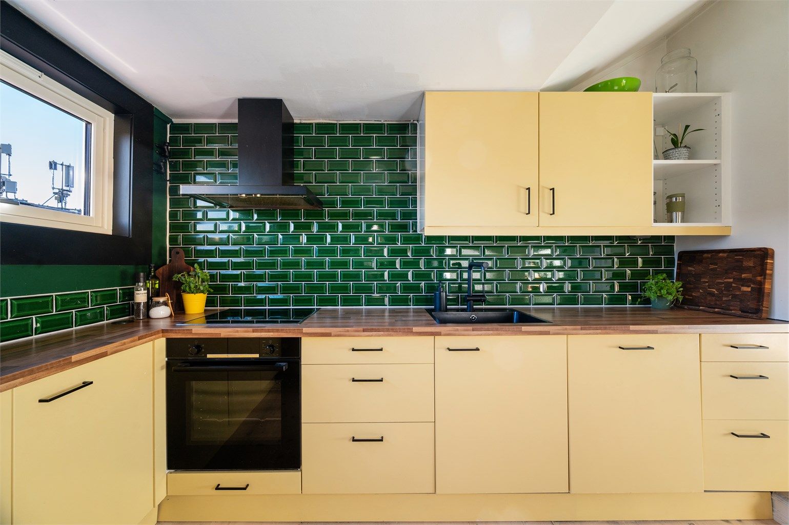 Benkeplate av laminat med nedfelt oppvaskkum med ett-greps kjøkkenarmatur, samt benkeskapsbelysning og stikkontakter over kjøkkenbenk.