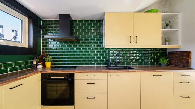 Benkeplate av laminat med nedfelt oppvaskkum med ett-greps kjøkkenarmatur, samt benkeskapsbelysning og stikkontakter over kjøkkenbenk.