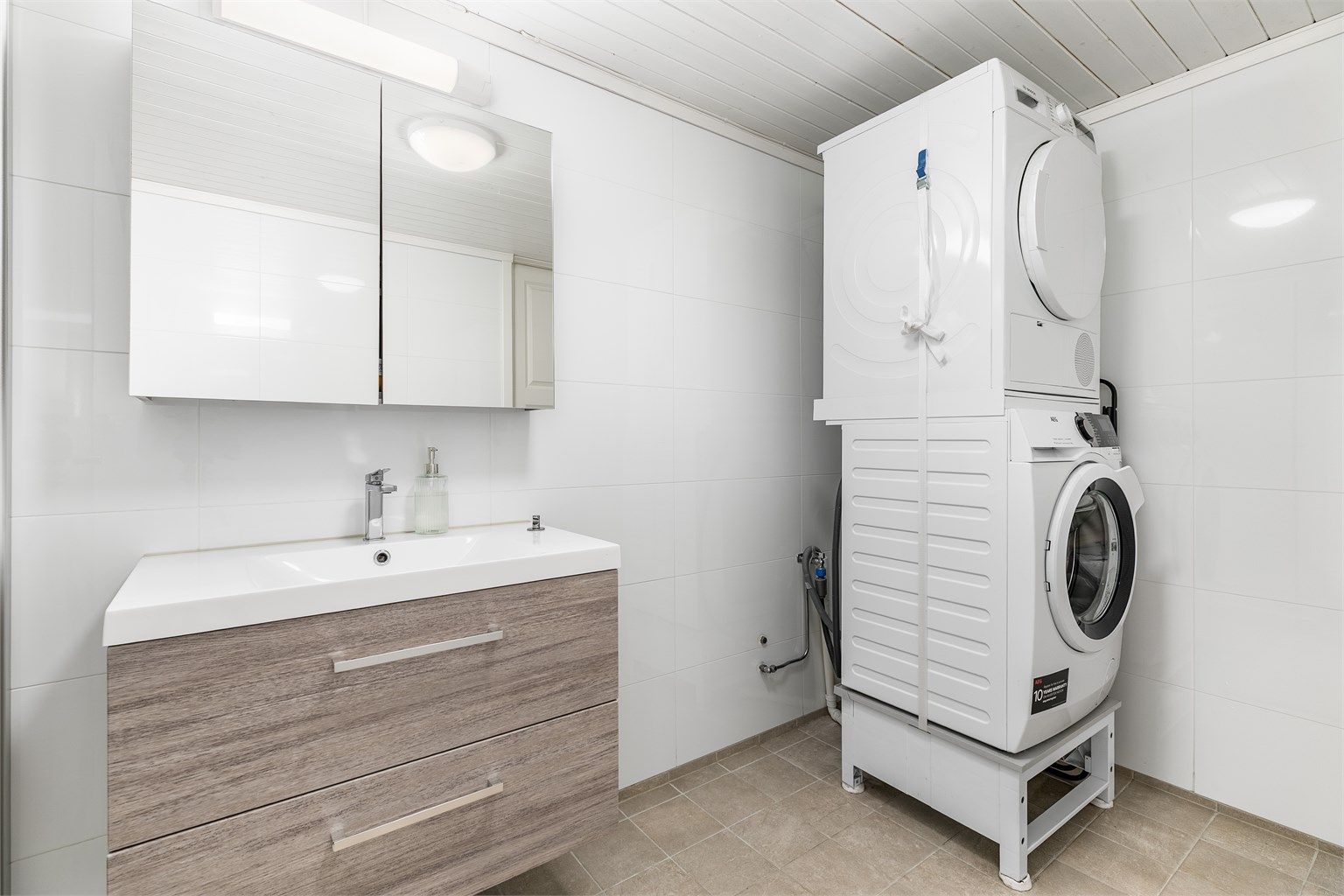 Kjellerbadet fungerer i i tillegg som vaskerom. Gulv og vegger er som på badet i andre etasje utført med fliser, gulvet også med varme.