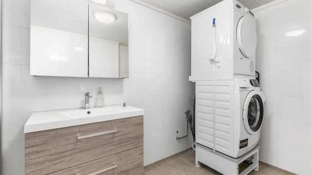 Kjellerbadet fungerer i i tillegg som vaskerom. Gulv og vegger er som på badet i andre etasje utført med fliser, gulvet også med varme.