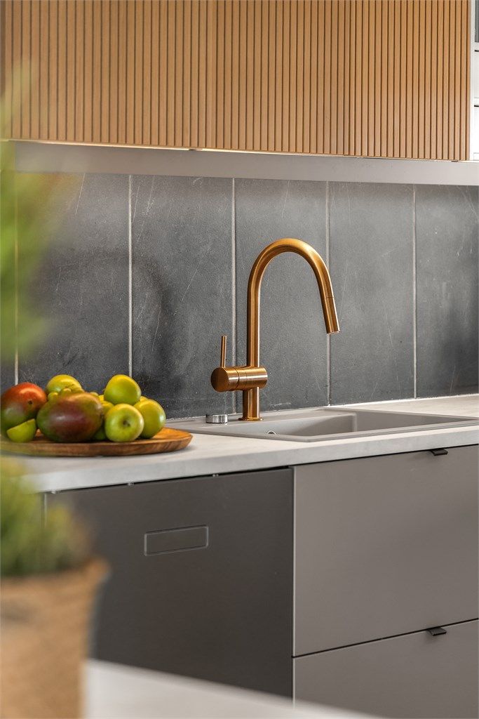 Moderne og stilrene materialvalg på kjøkkenet, med laminatbenkeplate og fliser på veggen mellom benk og overskap.