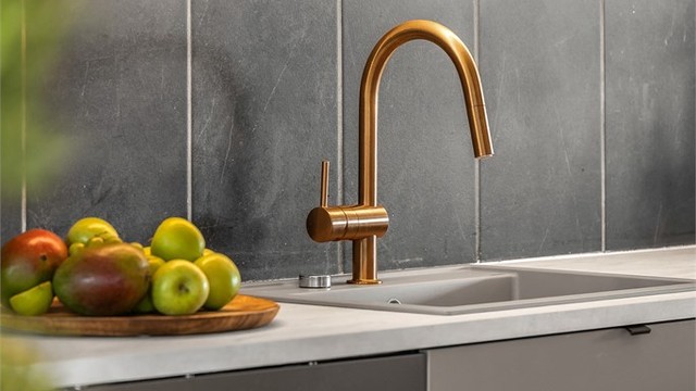 Moderne og stilrene materialvalg på kjøkkenet, med laminatbenkeplate og fliser på veggen mellom benk og overskap.