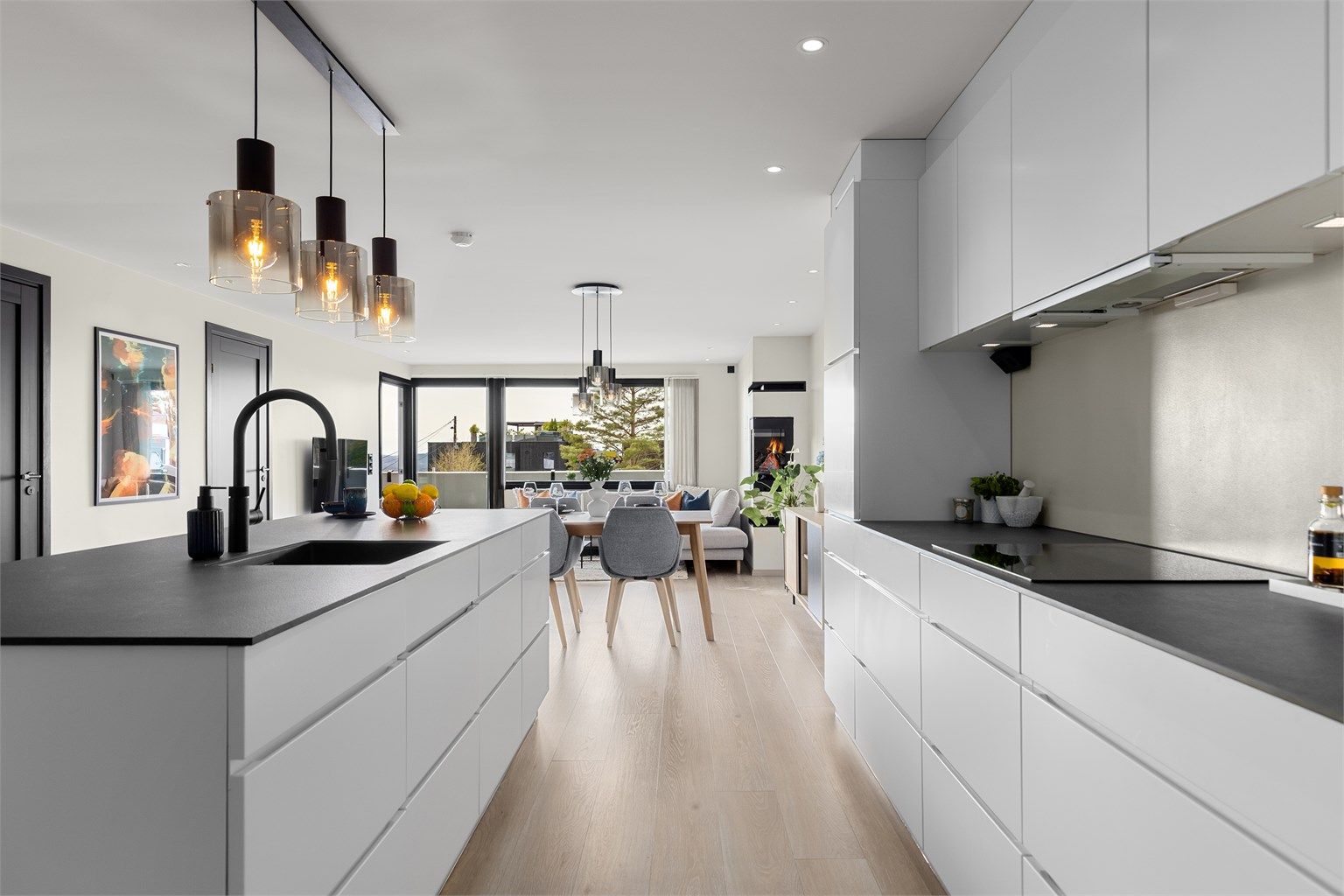 Den hvite innredningen med slette fronter gir en fin kontrast mot den mørke benkeplaten i kompaktlaminat