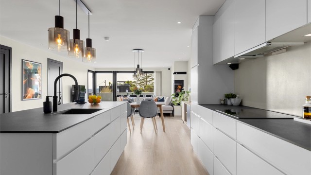 Den hvite innredningen med slette fronter gir en fin kontrast mot den mørke benkeplaten i kompaktlaminat