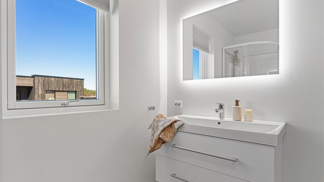Stort vindu gir naturlig lys, ventilasjon, servant med oppbevaring og speil med lys som gir et moderne uttrykk