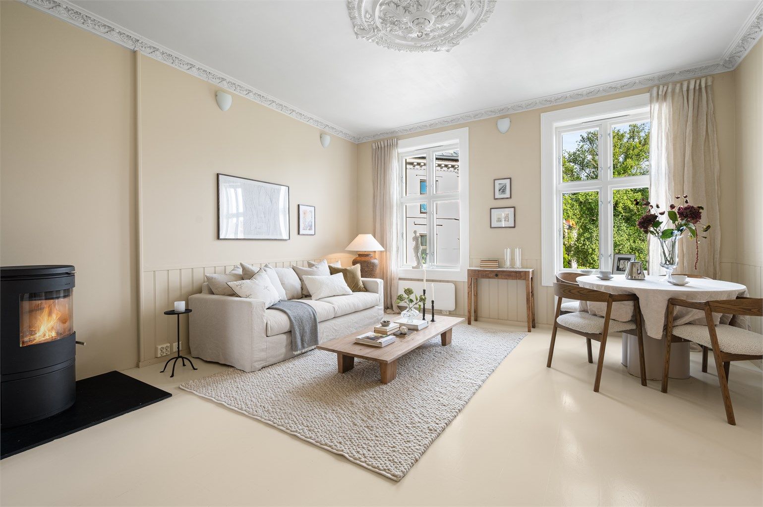omslig stue med plass til både sofagruppe og spisebord, med åpen forbindelse til hovedsoverommet.