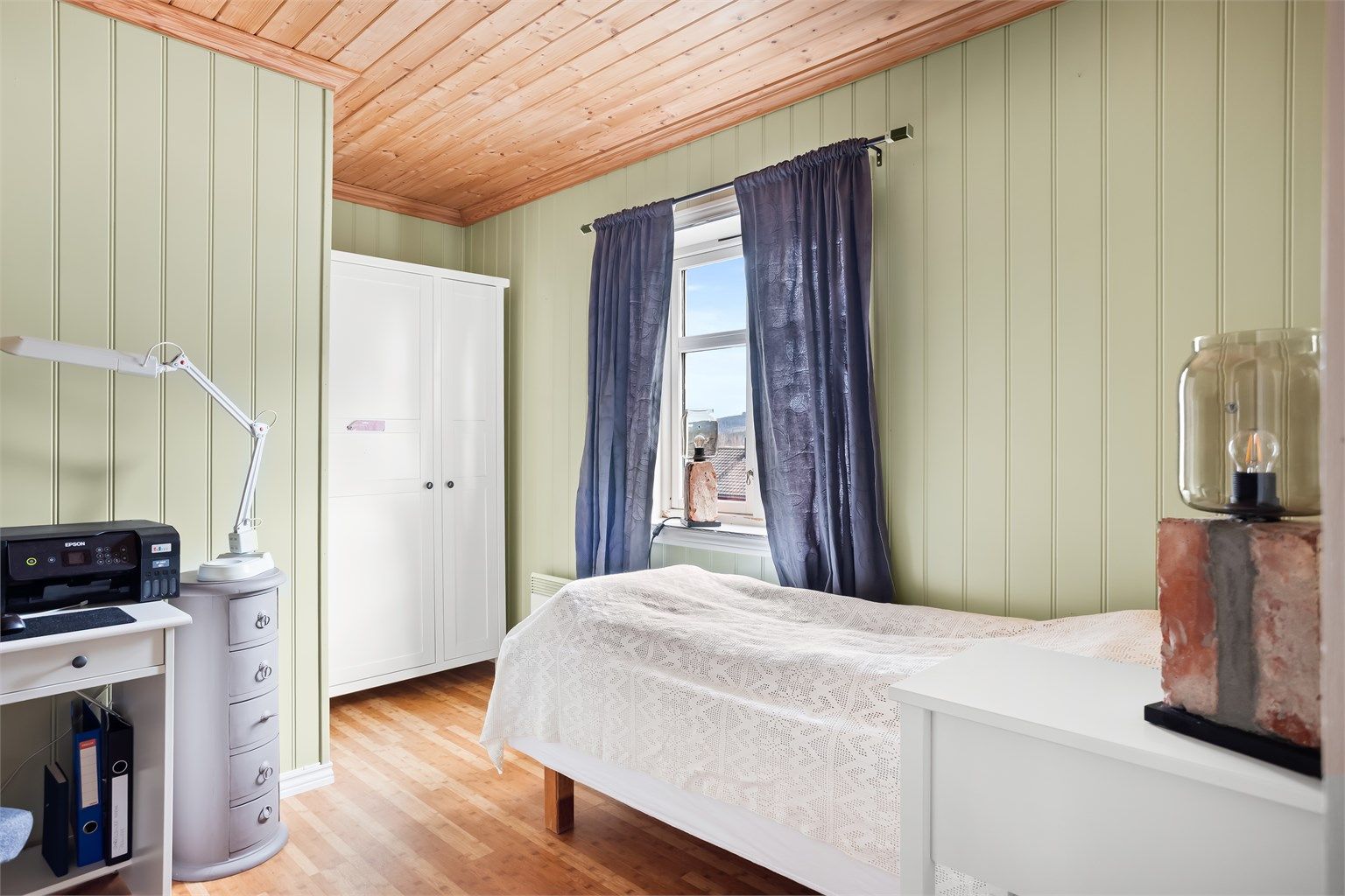 Sjarmerende soverom med lun atmosfære, flott lysinnslipp og plass til både seng og oppbevaring.