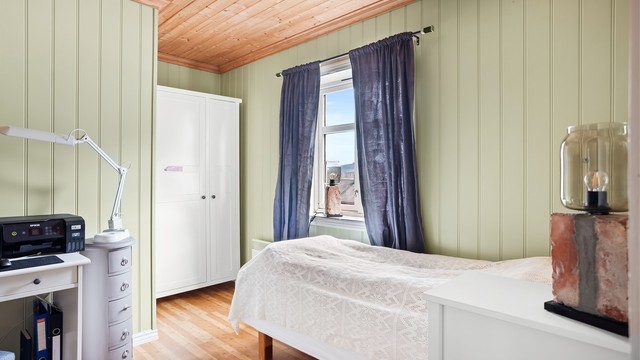 Sjarmerende soverom med lun atmosfære, flott lysinnslipp og plass til både seng og oppbevaring.
