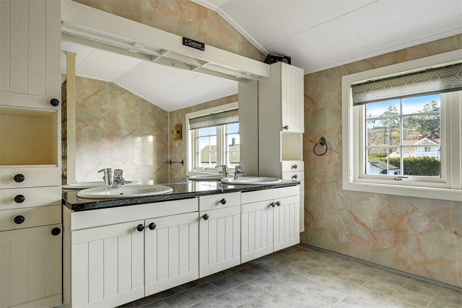 Badet har fliser på gulvet og godt med dagslys fra vinduene.